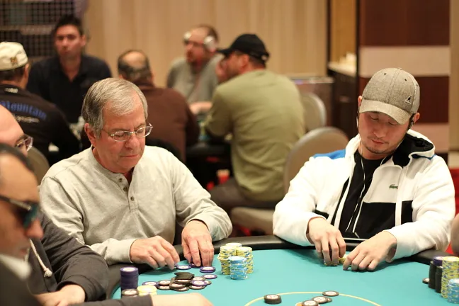 Joel Fishman stacking his new chips, while his dejected opponent examines his depleted stack